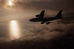 KC-135 Stratotanker flying near a body of water at sunrise